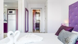 A hotel room with a bed, a purple headboard, a microwave, and a refrigerator. - Modern, with roof terrace and very close to the beach - Apartamento Caviar (Conil de la Frontera)