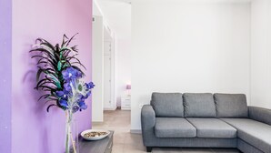 A living room with a grey sofa, a vase with flowers, and a purple wall. - Modern, with roof terrace and very close to the beach - Apartamento Caviar (Conil de la Frontera)