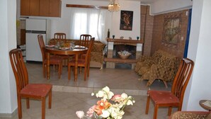 Un coin repas avec une table et des chaises en bois, une cheminée et un canapé à l’arrière-plan.