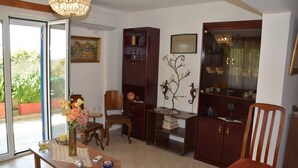 Un salon avec une table basse en bois, un fauteuil, une bibliothèque et un arbre décoratif en métal.