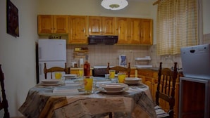 A dining area with a table set for four, wooden cabinets, a refrigerator, and a coffee maker.