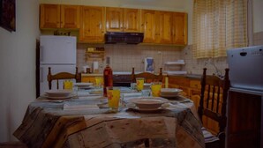 A kitchen with wooden cabinets, a dining table set with plates and glasses, and a refrigerator.