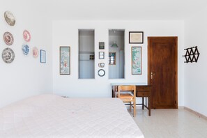 Ein Schlafzimmer mit Bett, Schreibtisch, Stuhl, Kleiderschrank und Wanddekorationen.