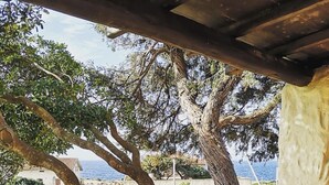 Un espacio al aire libre con una pérgola, árboles y vistas al mar.