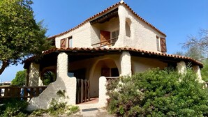 Una casa de dos pisos con techo de tejas, un balcón y una puerta de madera.