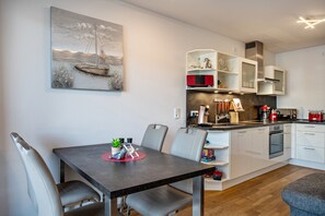 Een moderne keuken met witte kastjes, een inbouwoven en een magnetron.