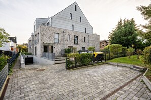 Een modern gebouw met een schuin dak, een verharde oprit en een verzorgde tuin.