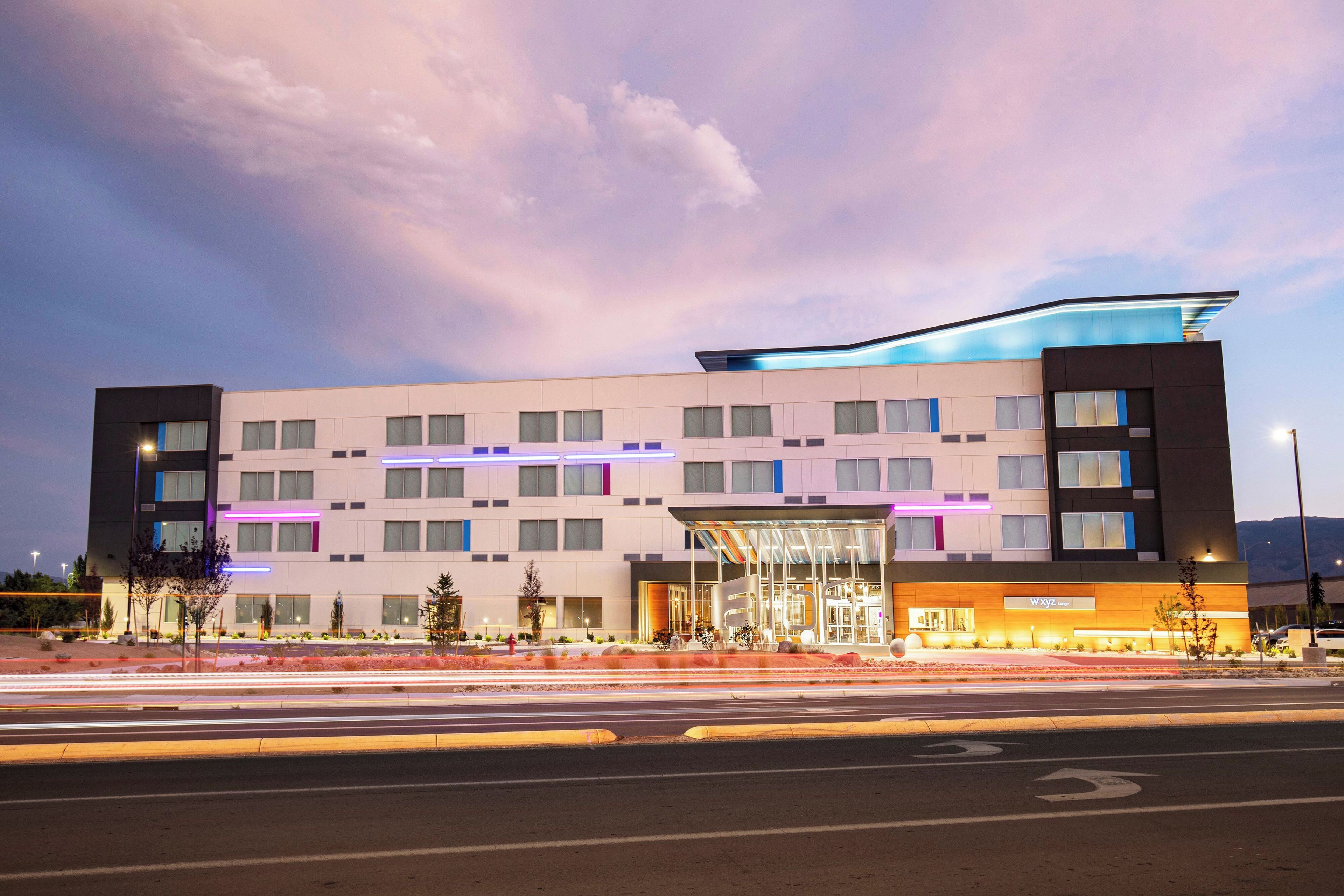 A modern hotel building with multiple floors, a covered entrance, and a parking lot.