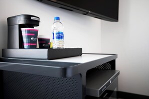 Un minibar con una macchina per il caffè, una bottiglia d'acqua e un vasetto di panna.