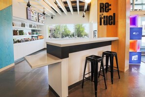 A modern bar area with a counter, stools, and a menu board. - Aloft by Marriott Reno-Tahoe International Airport (Reno)