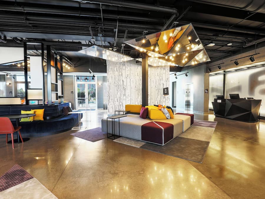 A modern lounge area with seating arrangements, a coffee machine, and a large window providing natural light.