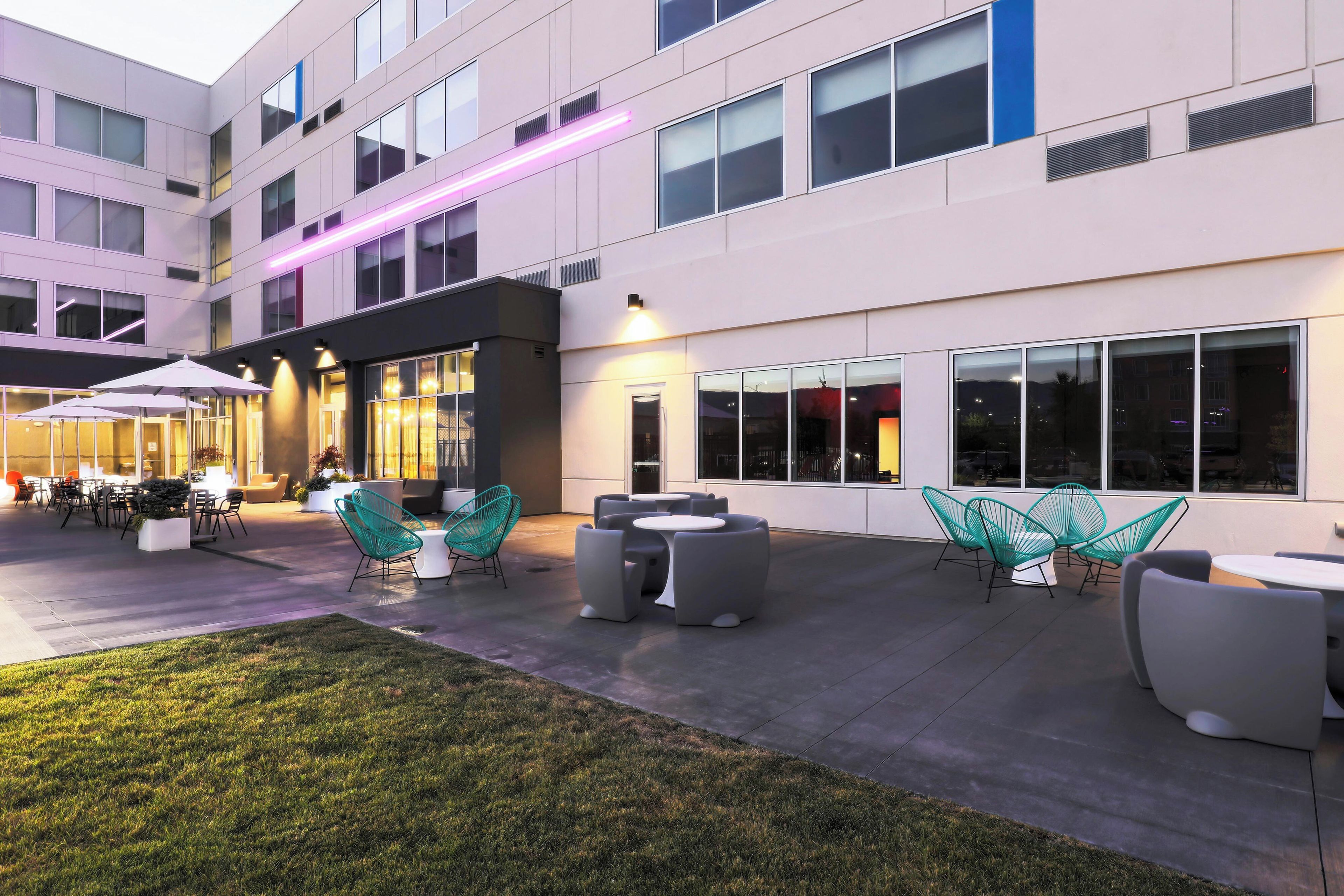 A modern building with outdoor seating and a well-maintained lawn.