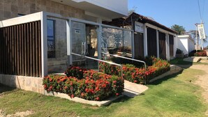 Un edificio moderno con entrada de vidrio, un letrero de VISA y flores rojas al frente.
