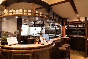 A bar area with a wooden counter, a plush lion toy, and a menu sign. - Stadthotel im Kolpinghaus Lingen (Lingen)
