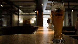 A glass of beer on a bar counter in a dimly lit bar with a modern interior. - Hotel Kolpinghaus Lingen (Lingen)