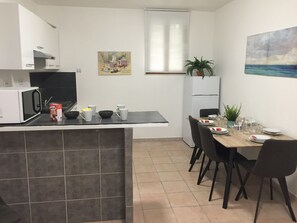 A compact kitchen with a dining area, featuring a microwave, coffee machine, and a dining table set for two. - MARSEILLE ST CHARLES / PORTE D’IX (Marseille)