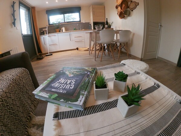 Una sala de estar moderna con un sofá, una mesa baja con una revista y plantas en macetas.