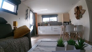 Una sala de estar moderna con un sofá, una mesa de centro con un letrero de bienvenida y vista a la cocina.