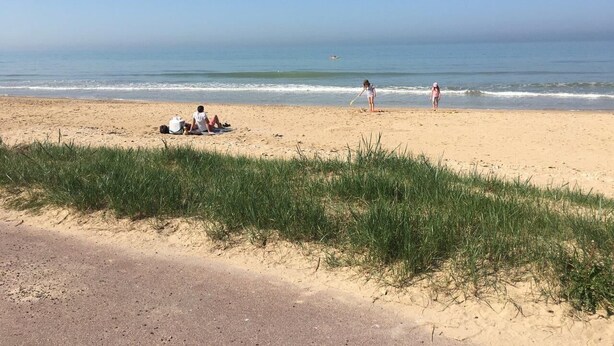 Una playa con gente sentada y caminando.