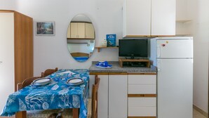 Una cocina compacta con una mesa de comedor, un televisor y un refrigerador.