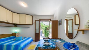 Un dormitorio con cama, mesita de noche, espejo y una vista al exterior.