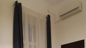 Una habitación con cama, sofá, puerta y ventana con cortinas.