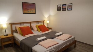 Una cama bien hecha con cabecera de madera, dos lámparas de noche y un cuadro en la pared superior.