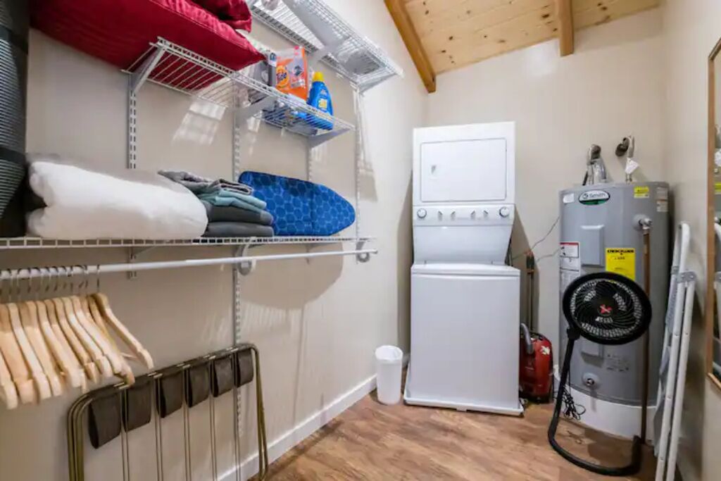 A laundry room with a white washing machine, a heater, and a fan.