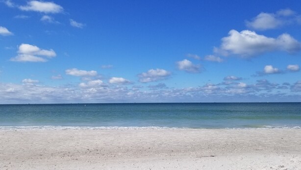 Una playa con cielo despejado y mar en calma.