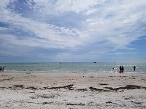 A beach with a sandy shore and calm sea, under a partly cloudy sky. - Beautiful St Pete Beach Vacation Condo Across the Street from the Beach (St. Pete Beach)