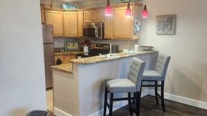 Una cocina moderna con armarios de madera, electrodomésticos de acero inoxidable y una isla central con taburetes de bar.
