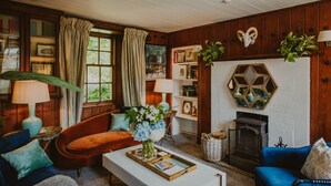 A cozy living room with a fireplace, wooden walls, and a bookshelf. - Historic Arcadia: Heritage Coachman Lodge on 2000-acre Seaside Estate (Portpatrick)