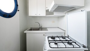 A kitchen with white cabinets, a stainless steel sink, a gas stove, and a window with a blue frame.