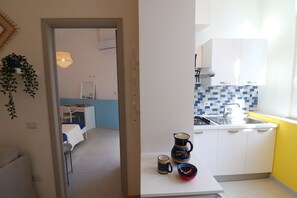 Keittiössä on valkoiset kaapit, sinivalkoinen laattaseinä, pesuallas ja ikkuna, josta tulee luonnonvaloa.