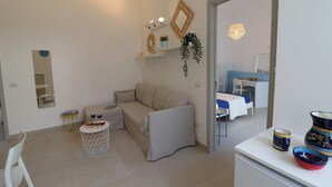 A modern living room with a sofa, a small round table, and a white cabinet. - Charming Holiday Apartment "Casa Vacanze Aura" with Air Conditioning (Otranto)