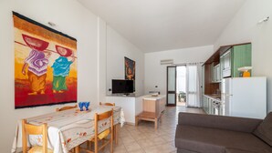 Un área de comedor con una mesa y sillas, un sofá, un televisor y obras de arte en las paredes.