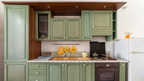 Una cocina con armarios verdes, una estufa y un refrigerador.