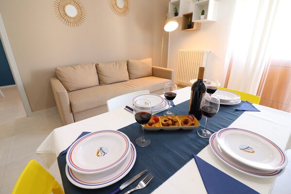 A dining table set with plates, glasses, a bottle, and a tray of food.