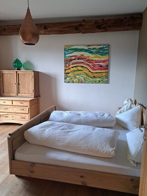 Un dormitorio con una cama de madera, un aparador de madera y un cuadro abstracto y colorido en la pared.