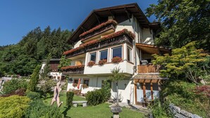 A two-story house with a balcony, surrounded by lush greenery and a clear blue sky. - Apartment 'Baumannhof Hasental - Adults Only' with Mountain View, Shared Garden and Wi-Fi (Gfrill/Tisens bei Lana)