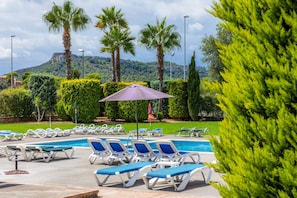 A pool area with lounge chairs and a palm tree.