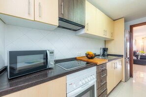 A modern kitchen with a microwave, stove, and oven, wooden cabinets, and a countertop.