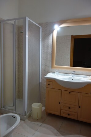 A bathroom with a glass shower enclosure, a sink with a mirror, and a toilet. - The Whale B&B (Alghero)