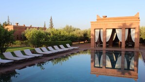 A pool area with lounge chairs and a building with curtains. - Domaine Casa Cecilia (Oulad Hassoune)