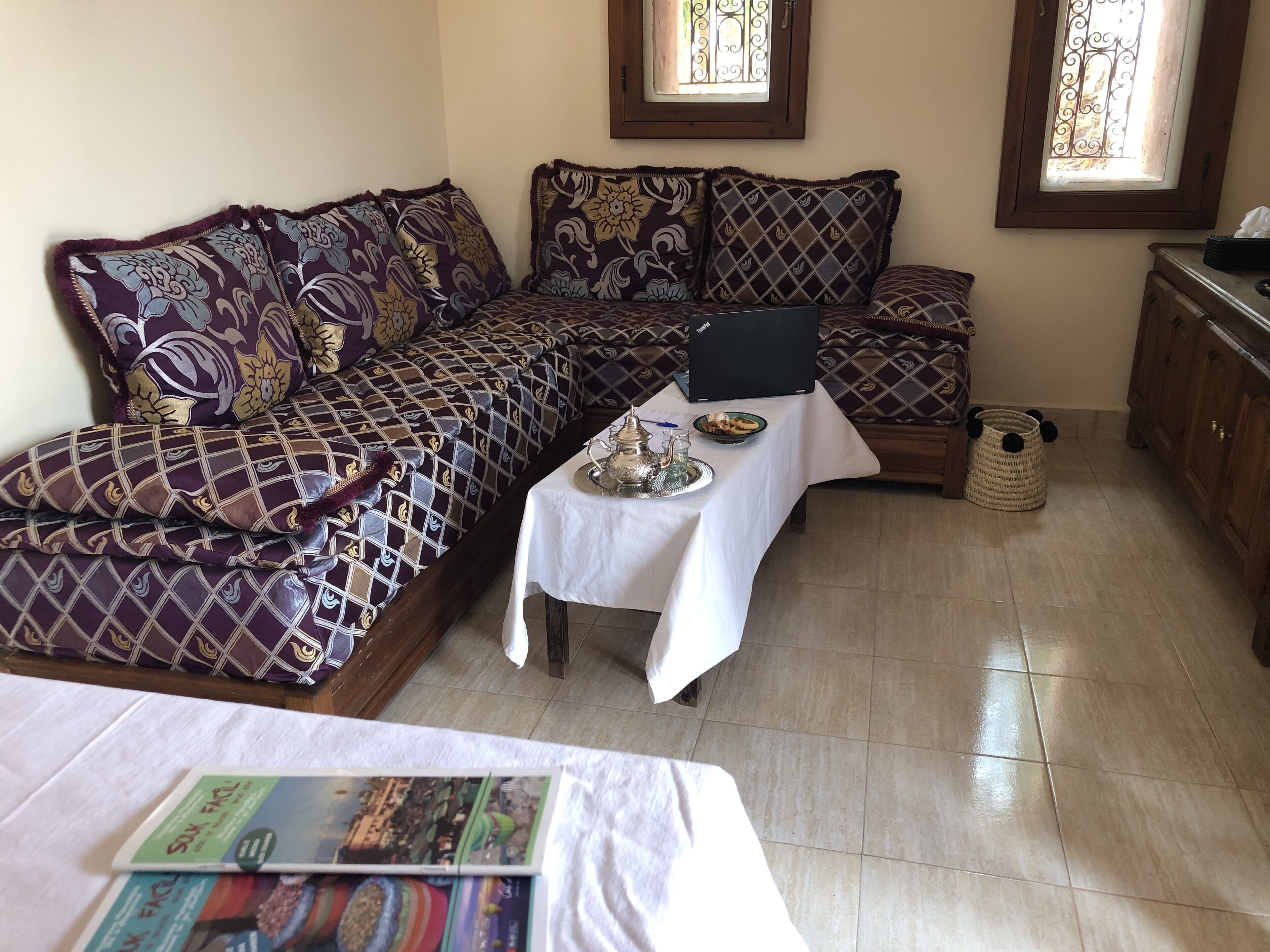 Ein gemütliches Zimmer mit einer Couch, einem kleinen Tisch mit Tablett und einem Laptop auf der Couch.