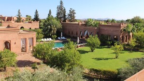 A courtyard with a swimming pool, lounge chairs, and a building with arches. - Domaine Casa Cecilia (Oulad Hassoune)
