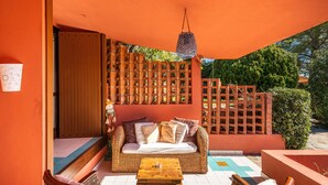 A room with a wicker sofa, a wooden table, and a patterned floor.
