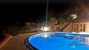 A swimming pool at night with surrounding stone walls and a staircase.