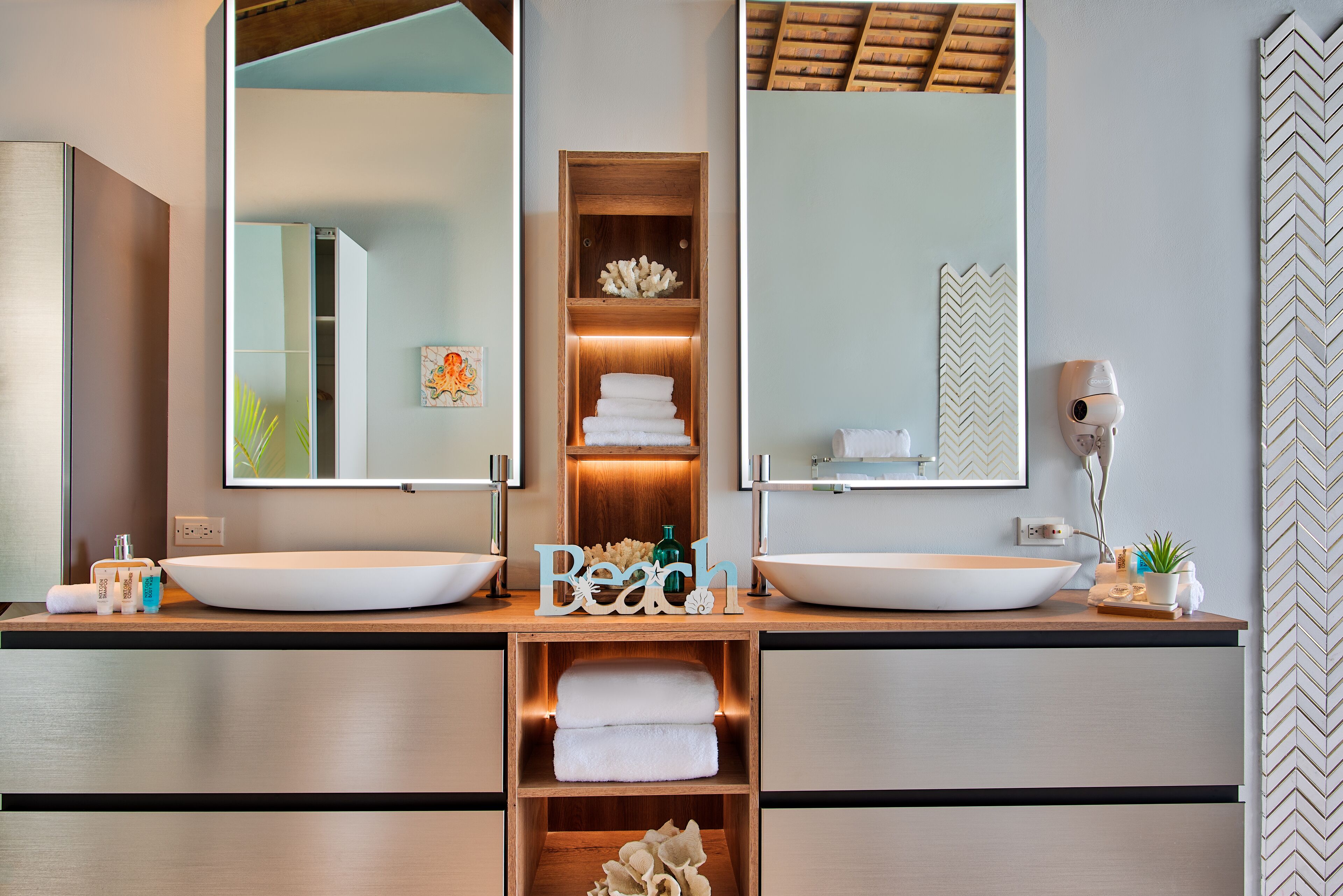 Een moderne badkamer met twee grote wastafels, een houten wastafelmeubel en een spiegel boven elke wastafel.