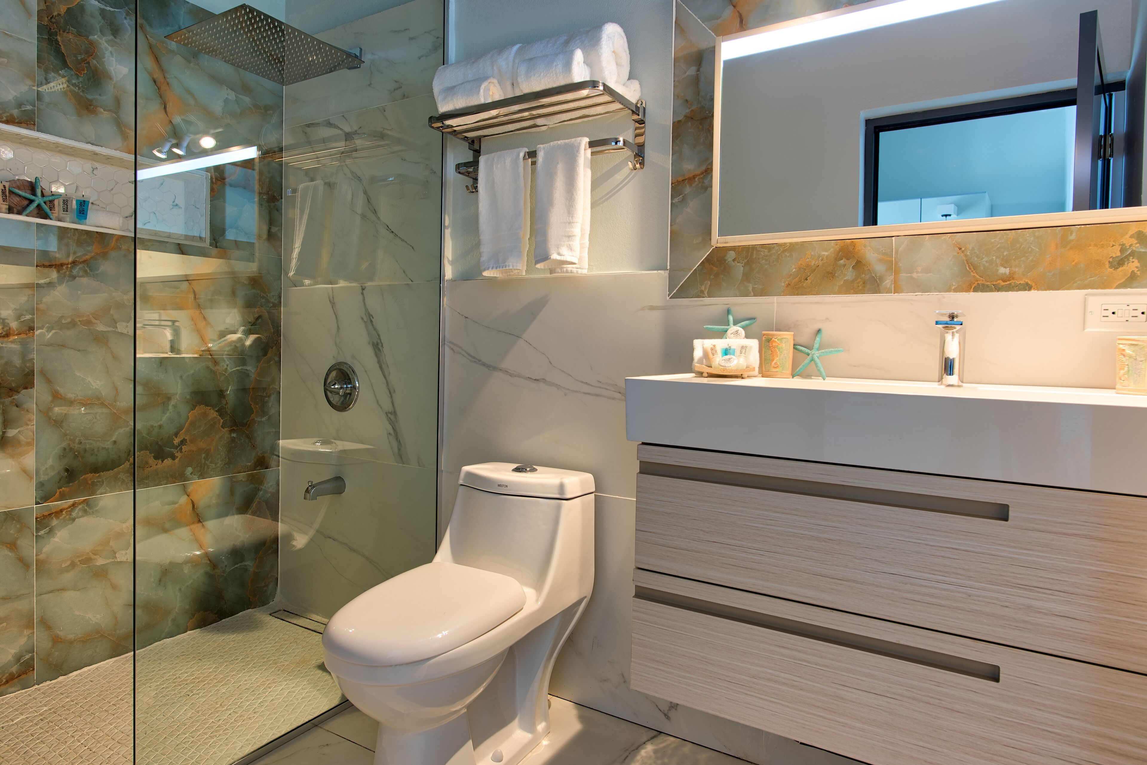 Une salle de bain moderne dotée d’une douche à parois de verre, de toilettes et d’un meuble-lavabo avec un miroir.